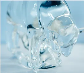 A close-up of a clear, light blue glass sculpture of a bull.